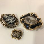 A group of three 19th century yellow metal and enamel mourning brooches: the first of shaped oval