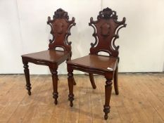 A pair of Victorian mahogany hall chairs, each back carved with scrolls and central vacant