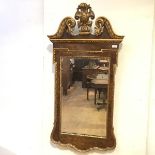 A George II style walnut and giltwood pier mirror, the swan neck crest and shaped apron enclosing