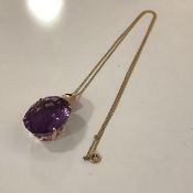 A large single stone amethyst pendant, the oval-cut stone claw-set in yellow metal on a tracelink