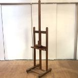 An elm easel, first half of the 20th century, the adjustable trestle frame, raised on castors. 264cm