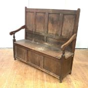 An 18th century oak and elm box settle, the quadruple panel back and hinged seat within open arms.