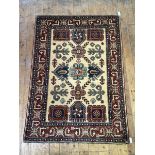 A hand-knotted wool rug of Kazak design, the dark cream field decorated with stylised flowerheads