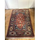 A hand-knotted wool small carpet of Caucasian design, with terracotta field decorated with