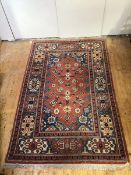 A hand-knotted wool small carpet of Caucasian design, with terracotta field decorated with