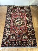 A Bakhtiari hand-knotted wool small carpet, the raspberry-sorbet field with central medallion