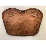 A copper plaque in the Art Nouveau taste, of shaped cartouche form, chased with putti, grapes and