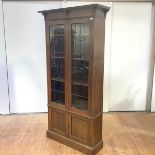 A Glasgow style Arts & Crafts bookcase, with projecting cornice and lead-glazed doors enclosing