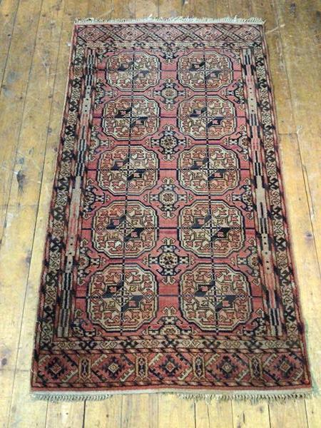 A Turkoman rug with two rows of five elephant feet, on red field surrounded by geometric borders