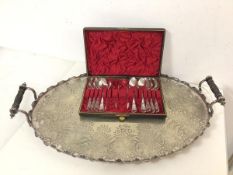 An Epns drinks tray with raised ebonised handles, with oval scalloped edge and foliate engraved base