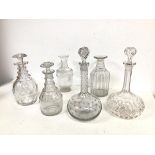 A collection of glass decanters of varying shapes and designs, two lacking stoppers, some chips
