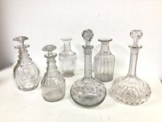 A collection of glass decanters of varying shapes and designs, two lacking stoppers, some chips