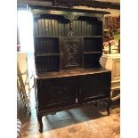 An early 20thc ebonised dresser, the plate rack with two shelves and central cupboard, with