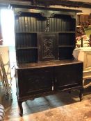 An early 20thc ebonised dresser, the plate rack with two shelves and central cupboard, with