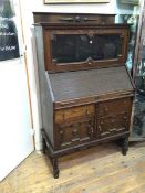 A 1920s/30s Tudor style oak bureau bookcase, with glazed fold up door above a tambour front, lacking