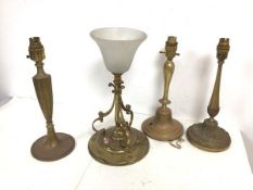 A group of brass and gilt metal table lamps, the largest with opaque shade over a tripod C scroll