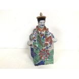 An early 20thc Chinese ceramic sculpture of a Seated Noble, with foliate decoration, and a blue seal