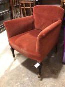 An Edwardian armchair in a brick red upholstery, on turned front supports terminating in four