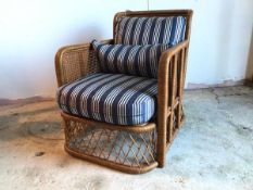 A stylish Ralph Lauren rattan lounge chair with striped upholstered back and seat cushion in navy
