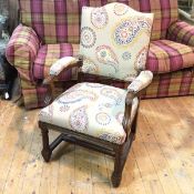 An oak open armchair, the back seat and arms in an oatmeal upholstery with paisley design, on fluted