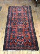 A Hamadan rug, with foliate design within three borders with scrolling leaf and flower design, red