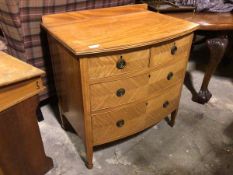 An early 20thc satinwood bow front chest of drawers with ledge back, the top with moulded edge above