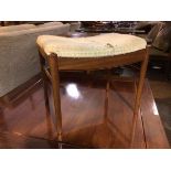 A mid century teak footstool, with upholstered top (a/f) on dished front and back apron, on turned