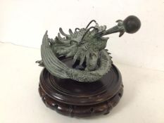 A Chinese cast metal Dragon and Pearl (20cm x 20cm x 25cm) on wooden circular base