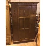 An oak wardrobe, the flat cornice supported by moulded brackets, with single panelled door enclosing