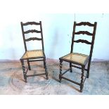 A pair of 1920s/30s oak side chairs with moulded ladder back above caned seats, with barley twist