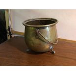 A brass and copper cauldron, lacking lid, with swing handle on three ball and claw feet (28cm x