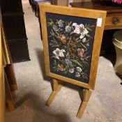 An oak firescreen/occasional table, the floral grospoint panel within a frame, can tilt and lock