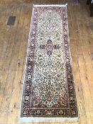 A Persian silk pile runner, the central medallion within an ivory field with scrolling vine and