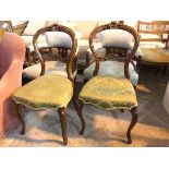 A pair of Victorian balloon back chairs with foliate carving to crest and back rail with damask