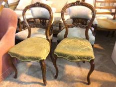 A pair of Victorian balloon back chairs with foliate carving to crest and back rail with damask