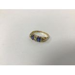 An 18ct gold ring set two blue stones separated by a pair of diamonds and flanked by single diamonds