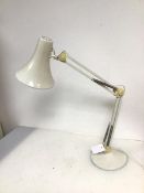 An anglepoise style table lamp with flared conical shade on adjustable body and circular base (