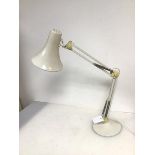 An anglepoise style table lamp with flared conical shade on adjustable body and circular base (