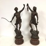 A pair of metal sculptures in bronze effect finish depicting a Man atop Tree Stump with Bow and a