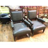 A pair of early 20thc armchairs with pierced top rail above a dark green leather upholstered back,