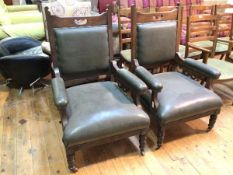 A pair of early 20thc armchairs with pierced top rail above a dark green leather upholstered back,