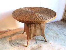 A circular wicker breakfast table on broad splay feet, stamped Made in Indonesia (78cm x d.97cm)