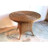 A circular wicker breakfast table on broad splay feet, stamped Made in Indonesia (78cm x d.97cm)