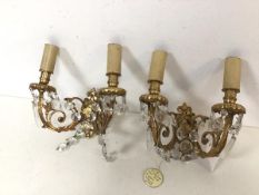 A pair of gilt metal wall lights, each with a pair of faux candles over a drip tray, on C scroll