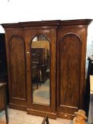 A late Victorian mahogany breakfront wardrobe with glazed central doors enclosing an arrangement