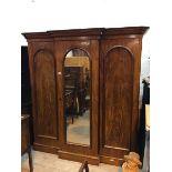 A late Victorian mahogany breakfront wardrobe with glazed central doors enclosing an arrangement