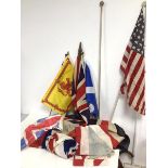 A collection of vintage flags, mostly Union Jacks but including an American Flag, with three