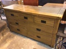 An oak long chest of drawers, with rectangular chanelled top above an arrangement of drawers, on