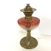 A glass and cast brass oil lamp, the gadrooned reservoir in a clear to red glass, base with a rococo