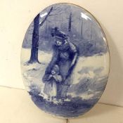 A blue and white wall plaque depicting a Woman and Child in Winter, with gilt edge, unmarked (35cm x